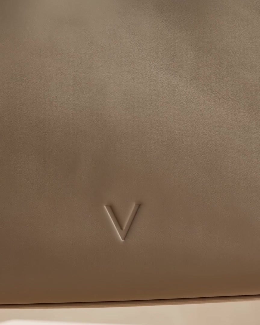 The embossed Véronne V, pressed cleanly into the front panel of the taupe cowhide.