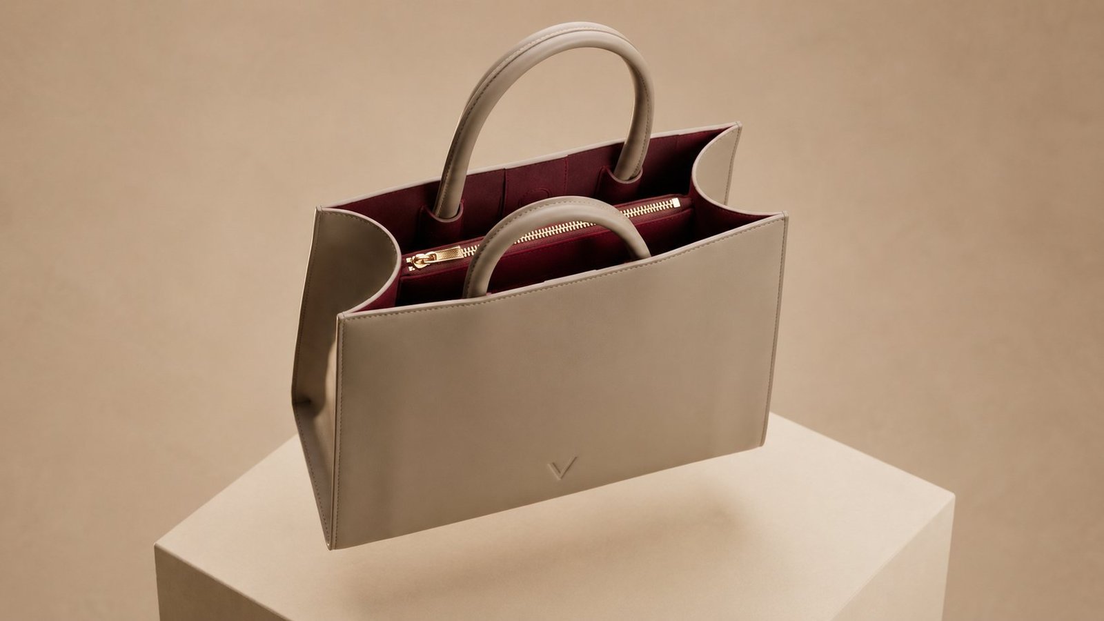 Looking down into the open Élan tote: dark burgundy suede lining, multiple compartments and gold-tone hardware.